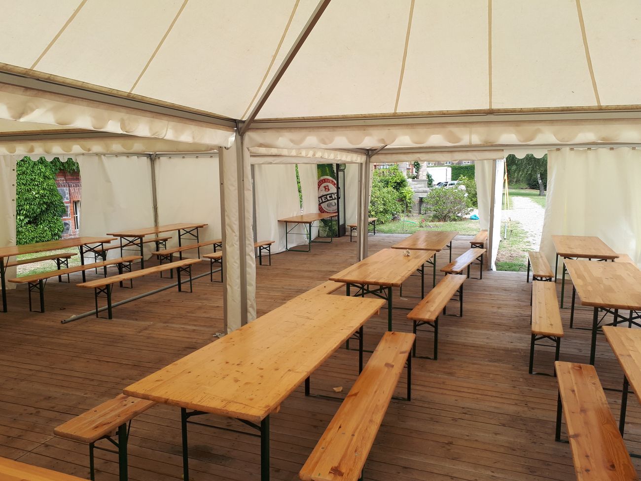 großes helles Zelt mit verlegtem Holzboden in dem Biertische stehen