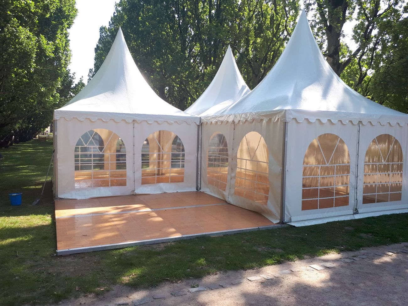 mehrere weiße Pagode-Zelte auf Holzboden, der auf der Wiese verlegt wurde