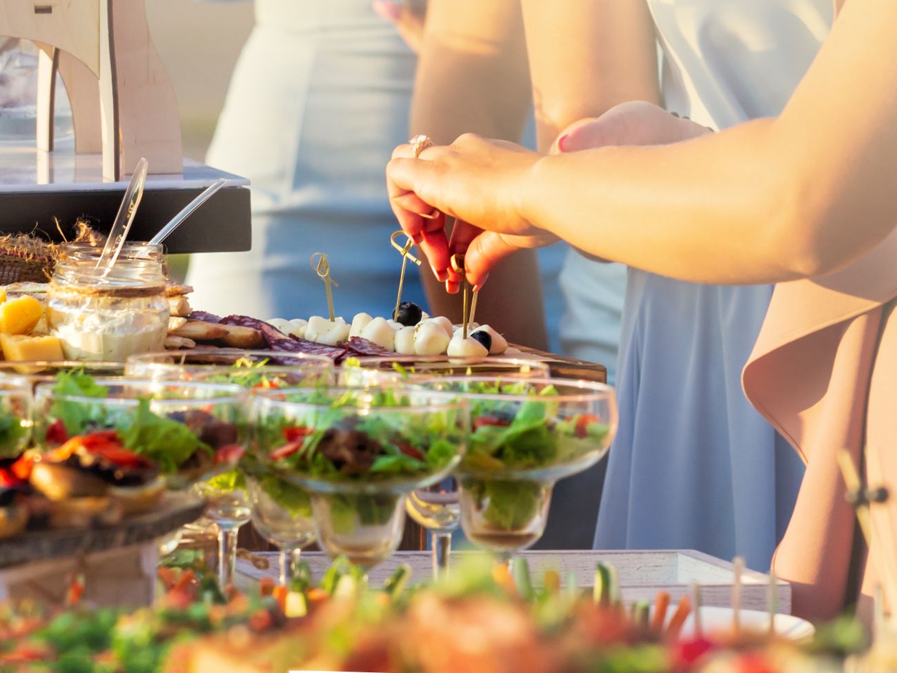 Sommerliches Buffet im Freien mit Gästen, die sich ihre Teller füllen