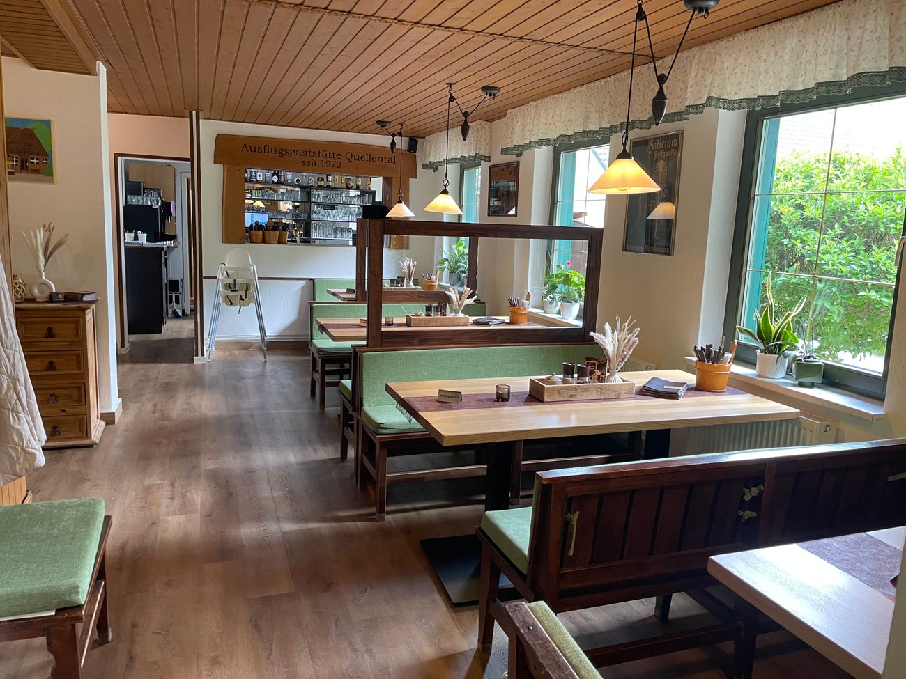 Holztische und grün gepolsterte Bänke in einem Gastraum