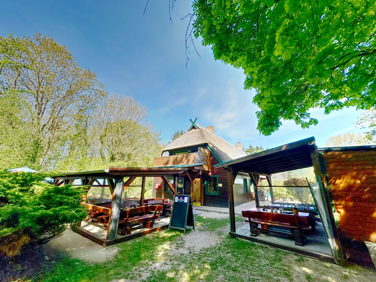 Außenansicht der Gaststätte mit überdachten Sitzgelegenheiten