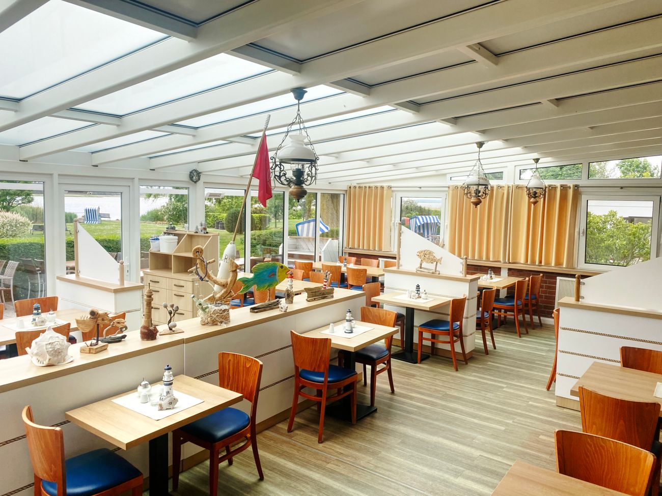 Heller Gastraum eines Restaurants mit gläserner Wand zur Terrasse