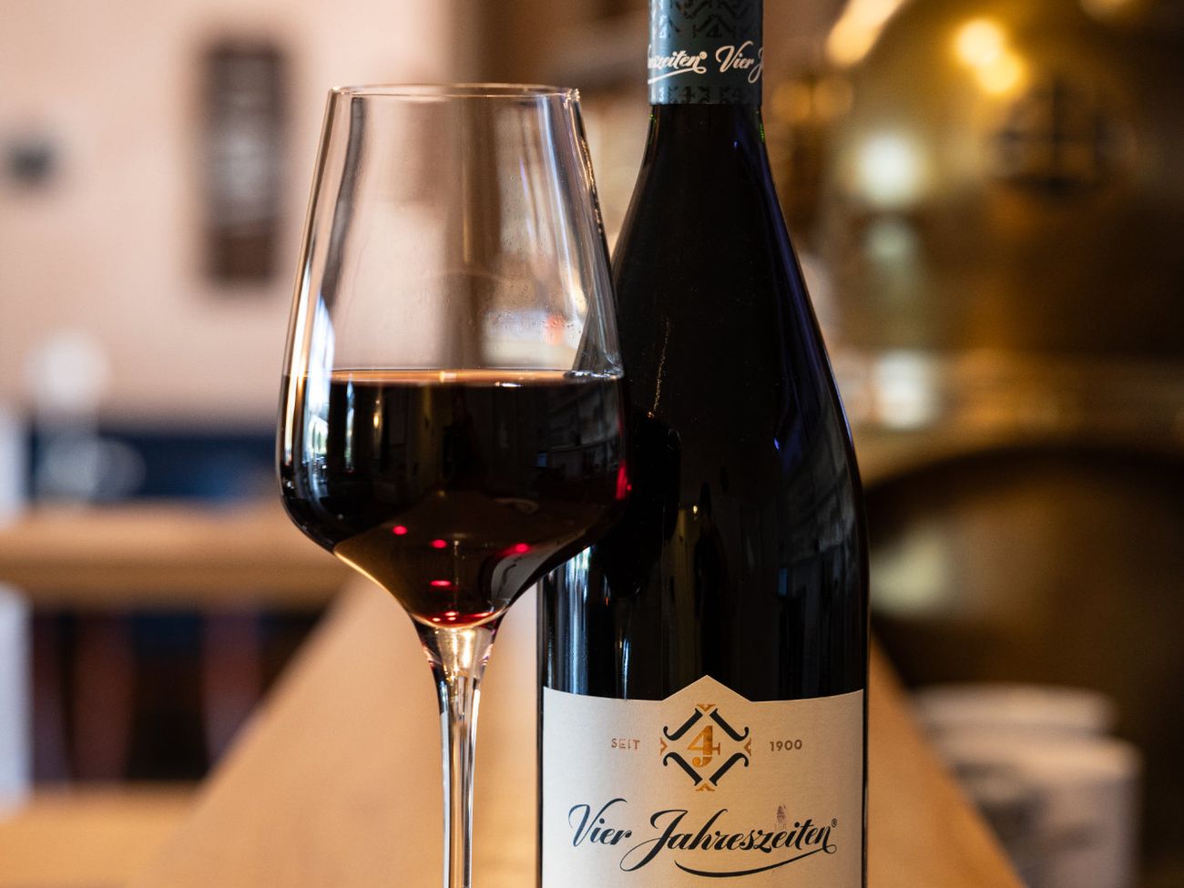 Flasche Rotwein mit halb gefülltem Rotweinglas auf einem Holztresen