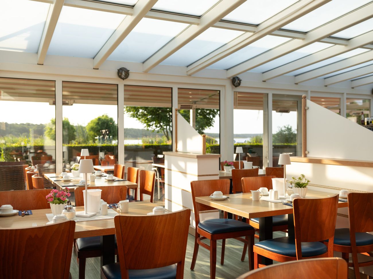 Wintergarten eines Restaurants mit eingedeckten Frühstückstischen