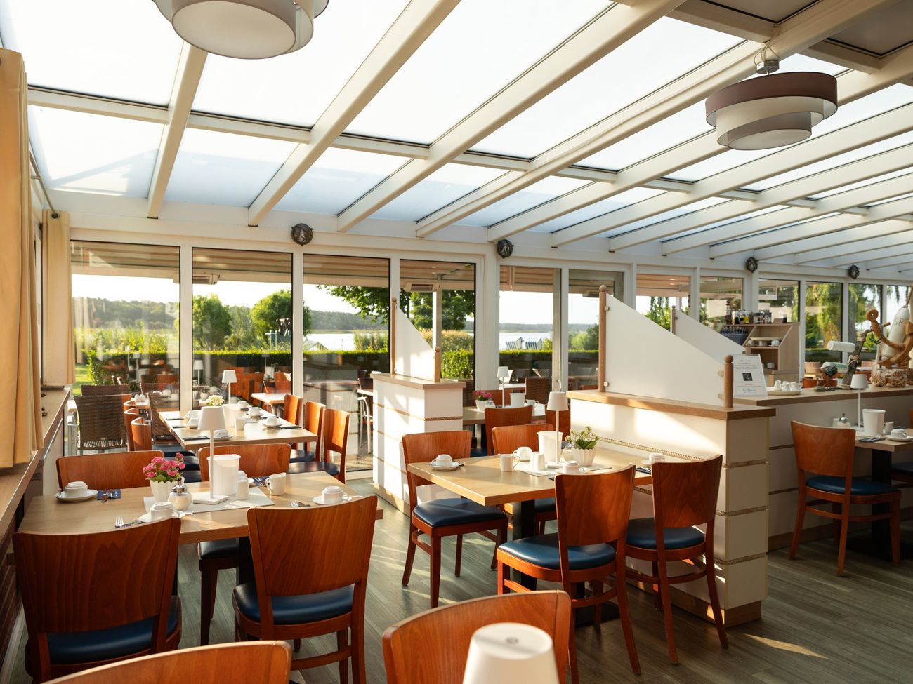 Wintergarten eines Restaurants mit eingedeckten Frühstückstischen