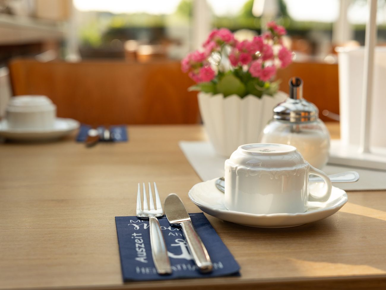 Besteck und Kaffeetassen auf einem eingedeckten Frühstückstisch