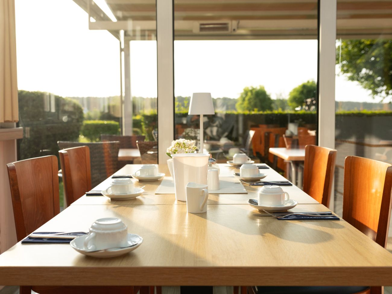 Für das Frühstück eingedeckter Tisch direkt am Fenster mit Blick auf die Terrasse