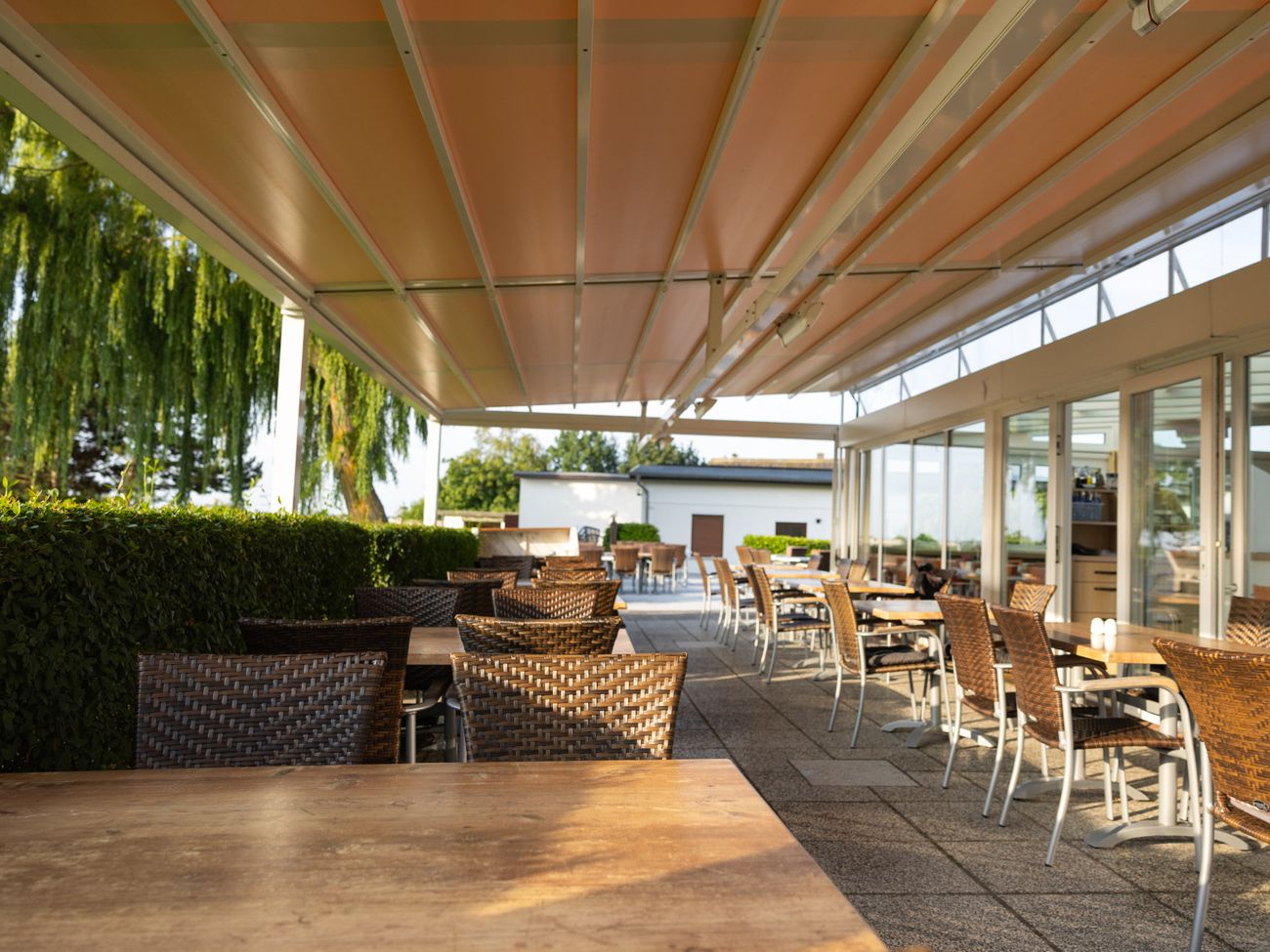 Tische und Stühle in braun unter einer großen Markise