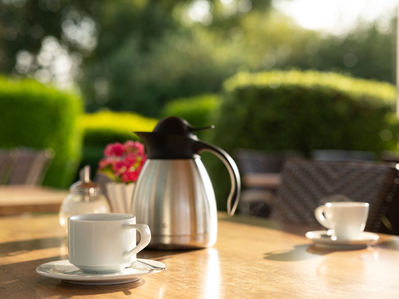 2 Kaffeetassen und eine Thermoskanne auf einem Tisch im Garten