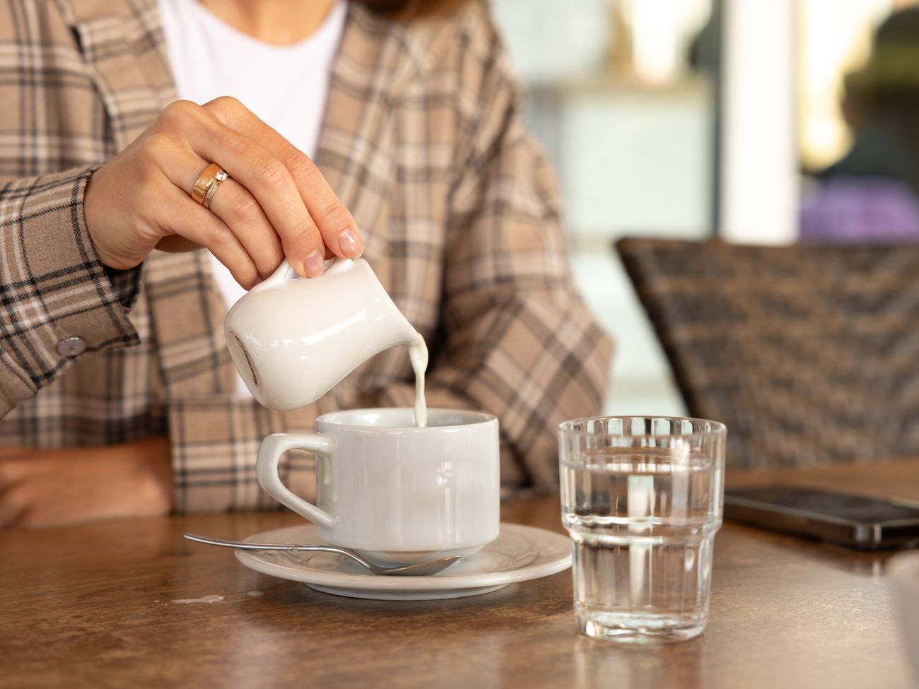 Eine Frau kippt Milch in ihren Kaffee