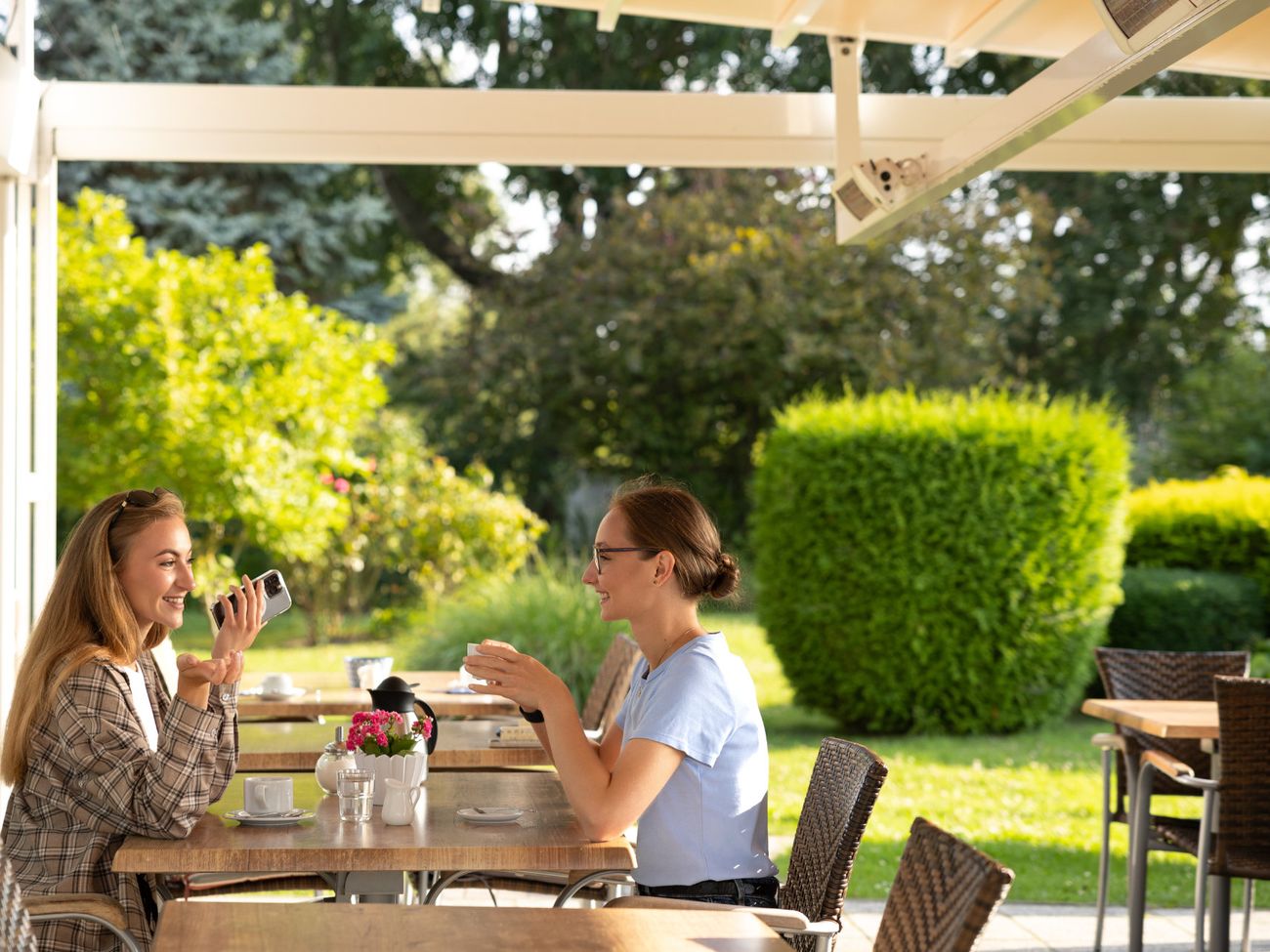 2 Frauen unterhalten sich bei einer Tassee Kaffee auf der Gartenterrasse
