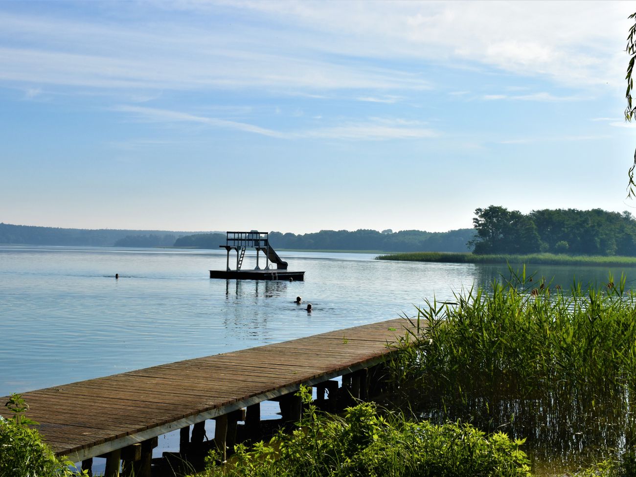 Holzsteg am See, auf dem Wasser eine Wasserrutsche