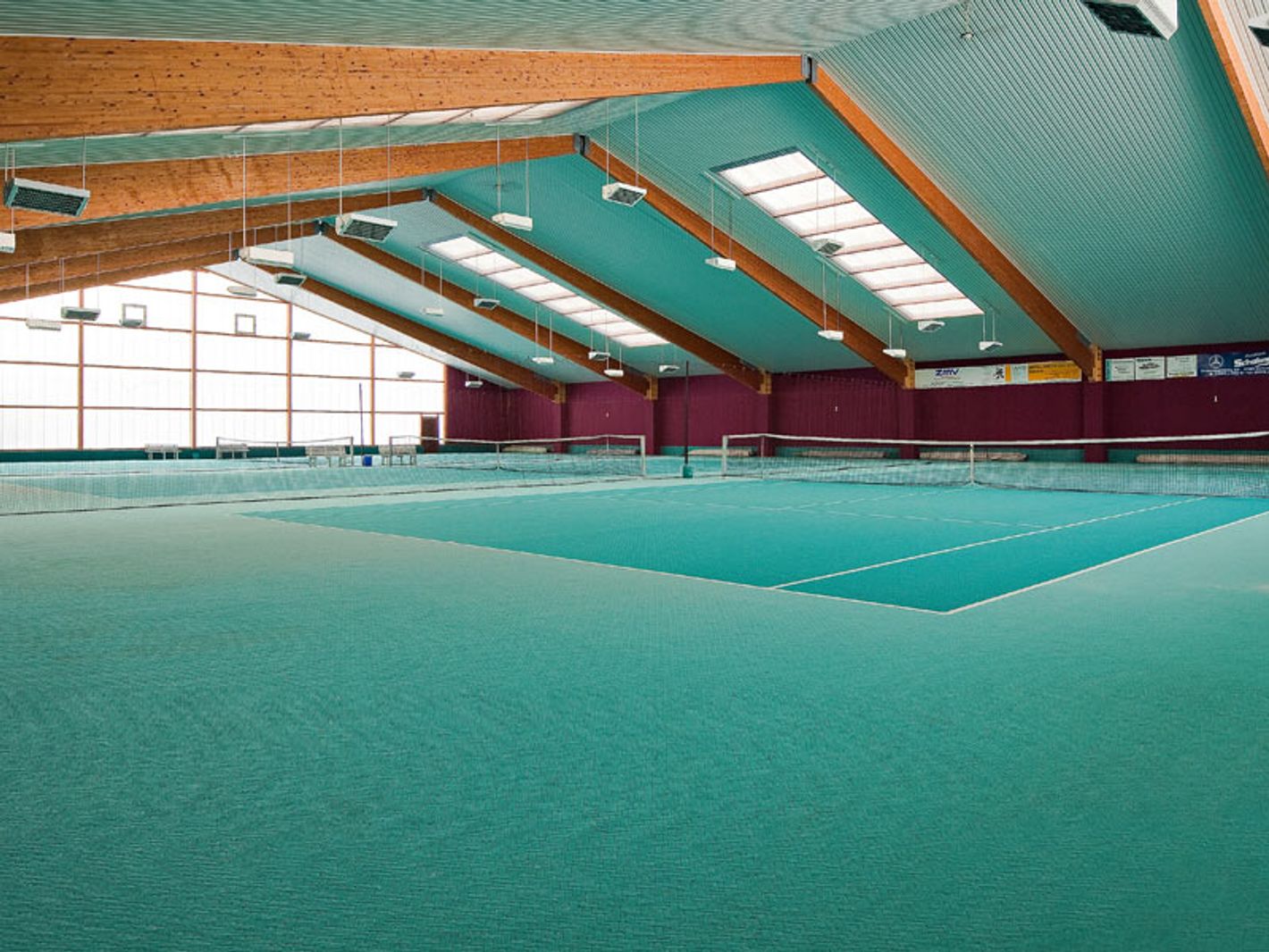 Tennishalle mit 3 Plätzen und grün-türkisem Bodenbelag und Blechdach