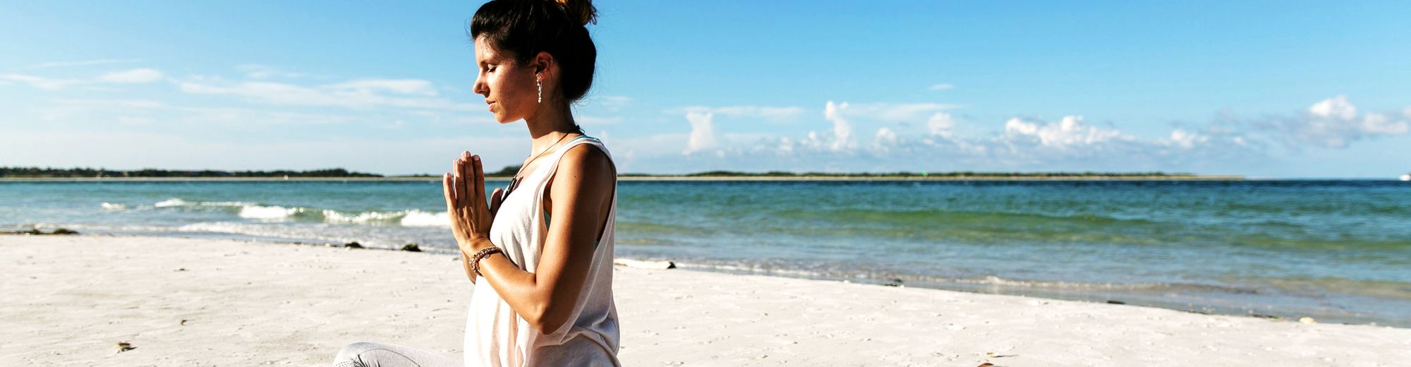 Frau macht Yoga am Strand