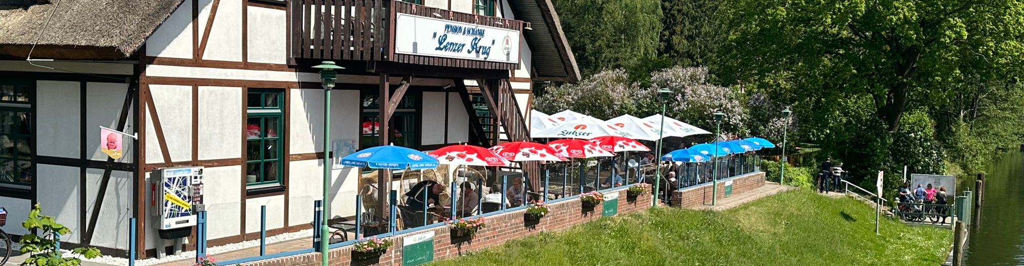 Außenansicht des Lenzer Krugs mit Terrasse und Sonnenschirmen
