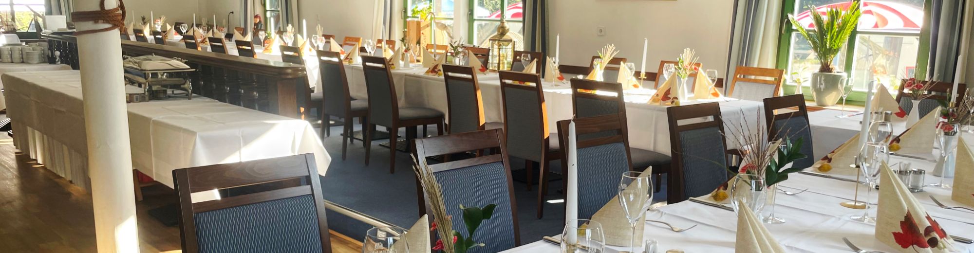 Lange herbstlich eingedeckte Tafel in einem großen hellen Raum