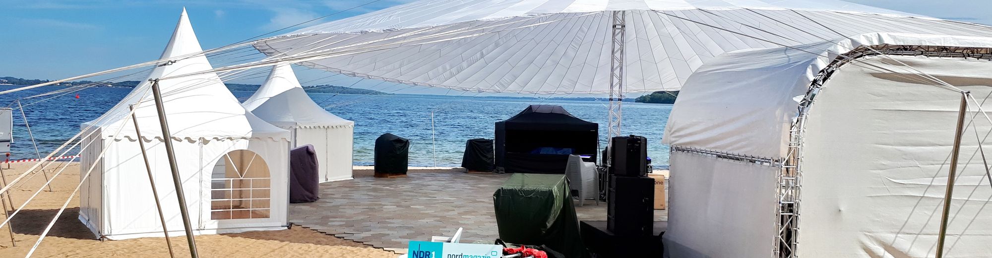 Zelte und technisches Equipment am Strand aufgebaut