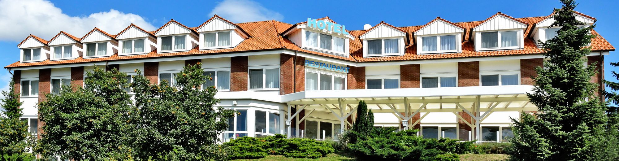 Hotel Trebeltal, Außenansicht des Hotels mit grünem Rasen und blauem Himmel