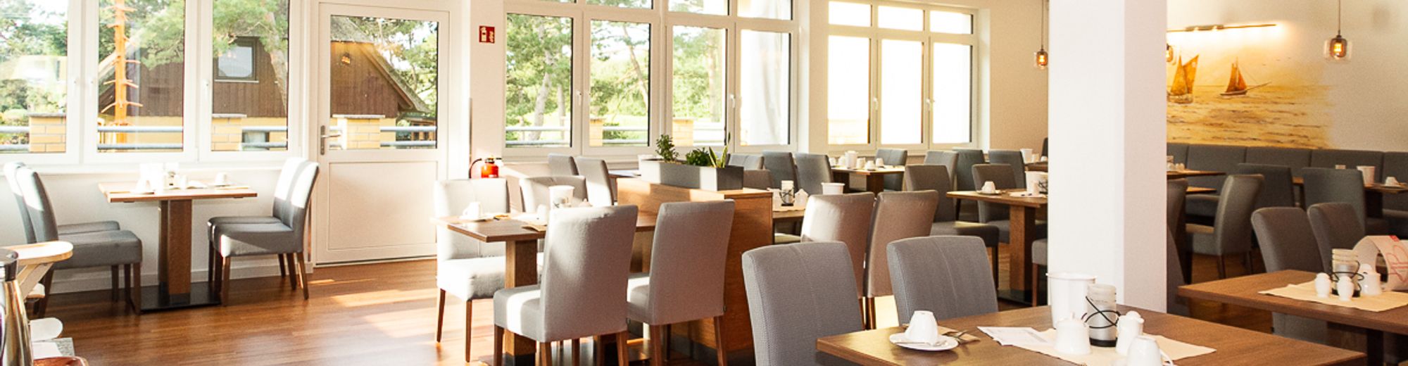 Helles, freundliches Restaurant mit grauen Stühlen und Holztischen