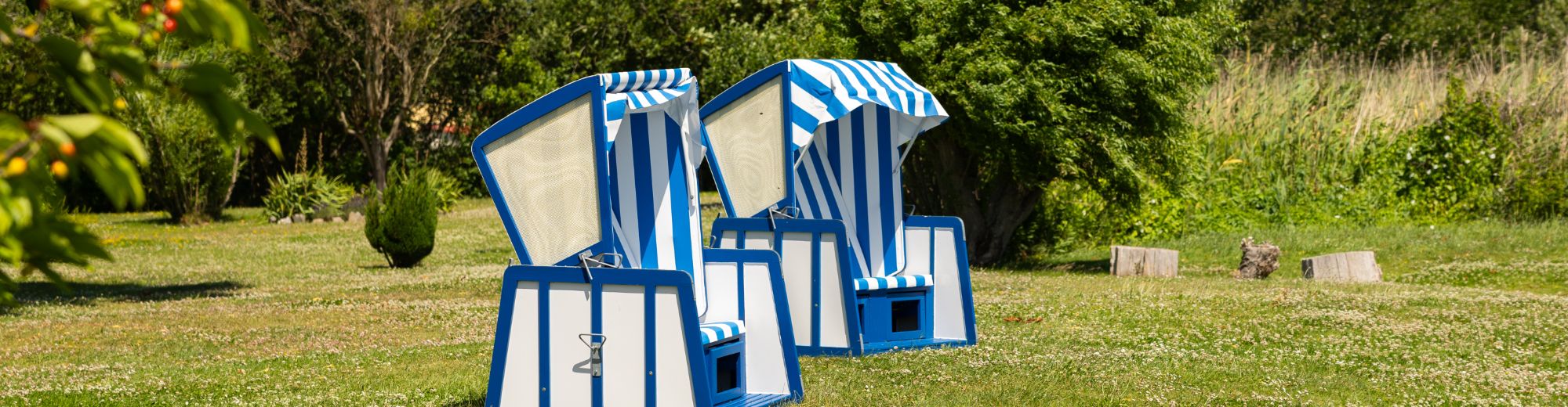 2 blau-weiße Strandkörbe auf gepflegtem Rasen in einem großen Garten