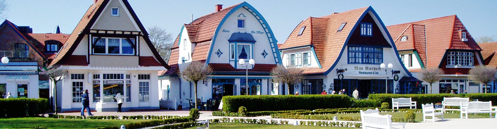kleine restaurierte Häuschen in weiß und blau, davor eine Parkanlage mit Rasen und Hecken