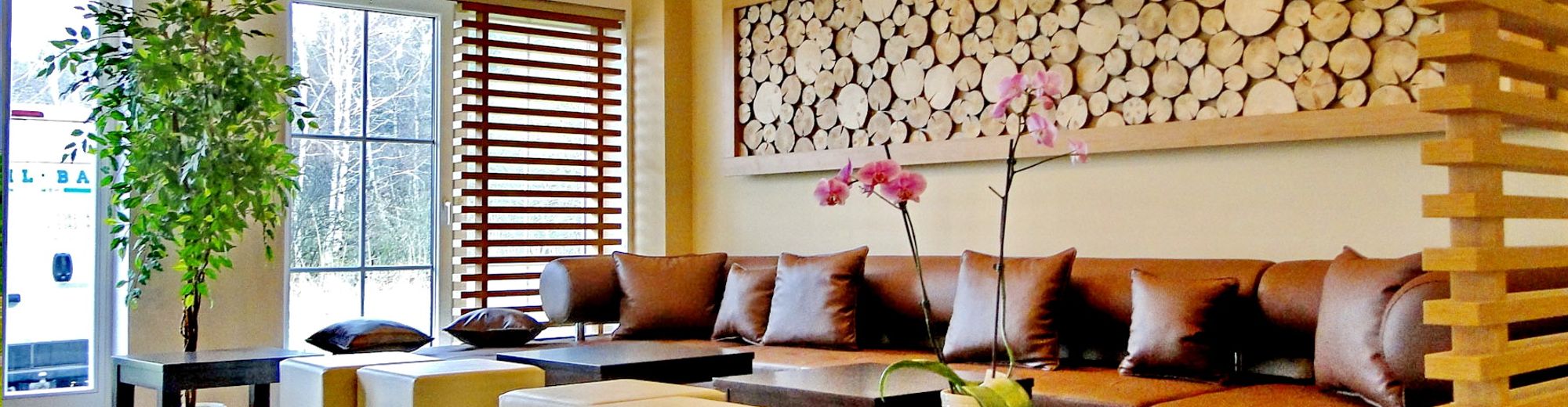 Lobby des Hotels Friesenhof mit Holzelementen an den Wänden, Ledermöbel in Brauntönen und kleinen Holztischchen