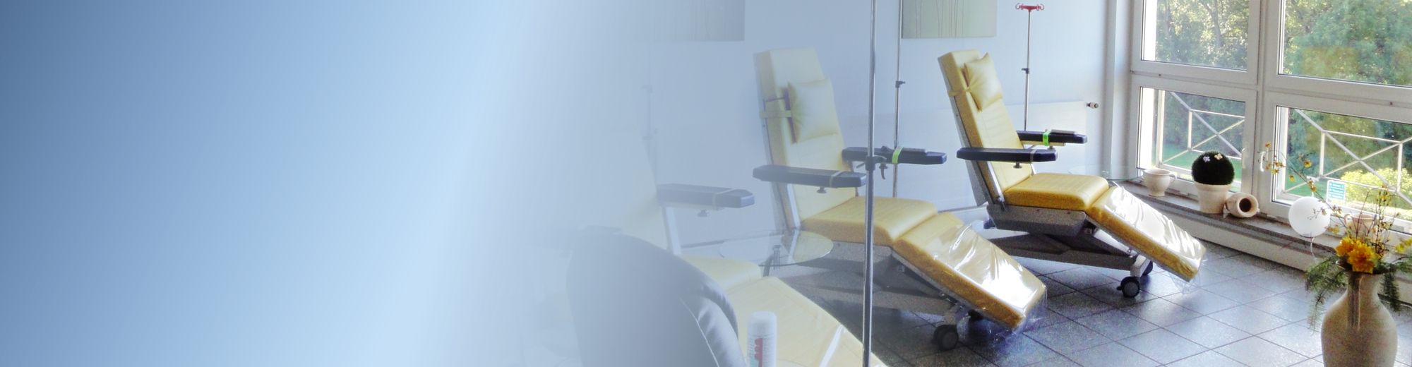 Therapieraum mit gelben Liegesesseln und Blick aus dem großen Fenster ins Grüne