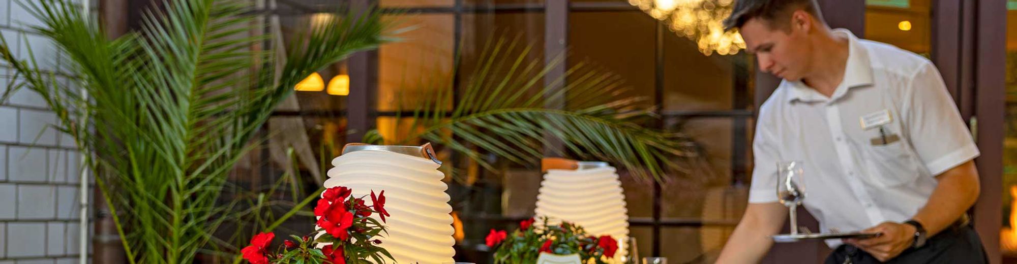 ein Kellner deckt Tische auf einer Terrasse ein