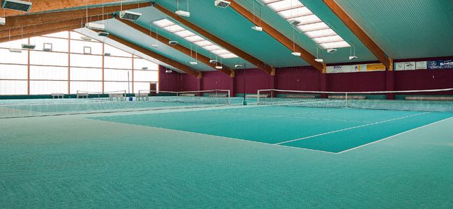 Tennishalle mit 3 Plätzen und grün-türkisem Bodenbelag und Blechdach