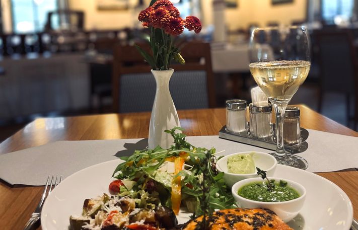 Gedeckter Restauranttisch mit einem Glas Weißwein und gebratenem Fisch
