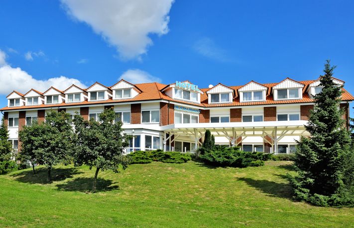 Hotel Trebeltal, Außenansicht des Hotels mit grünem Rasen und blauem Himmel
