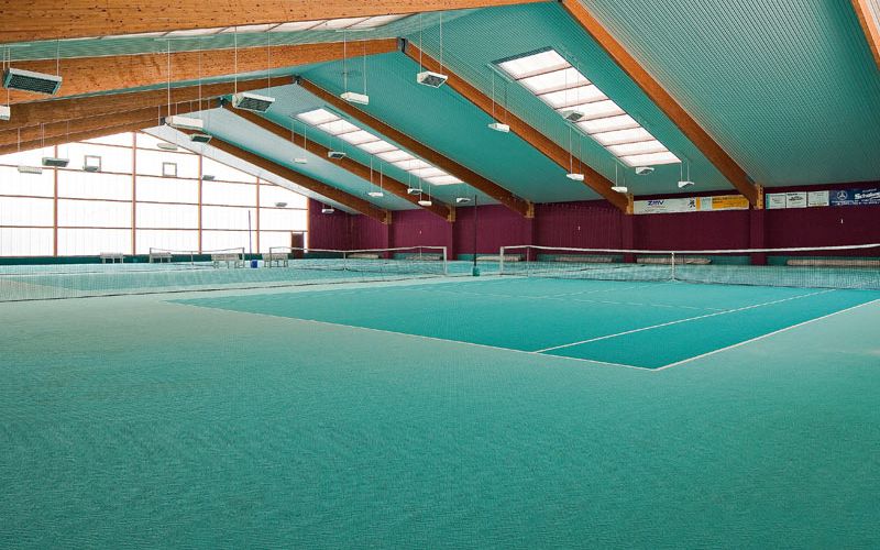 Tennishalle mit 3 Plätzen und grün-türkisem Bodenbelag und Blechdach